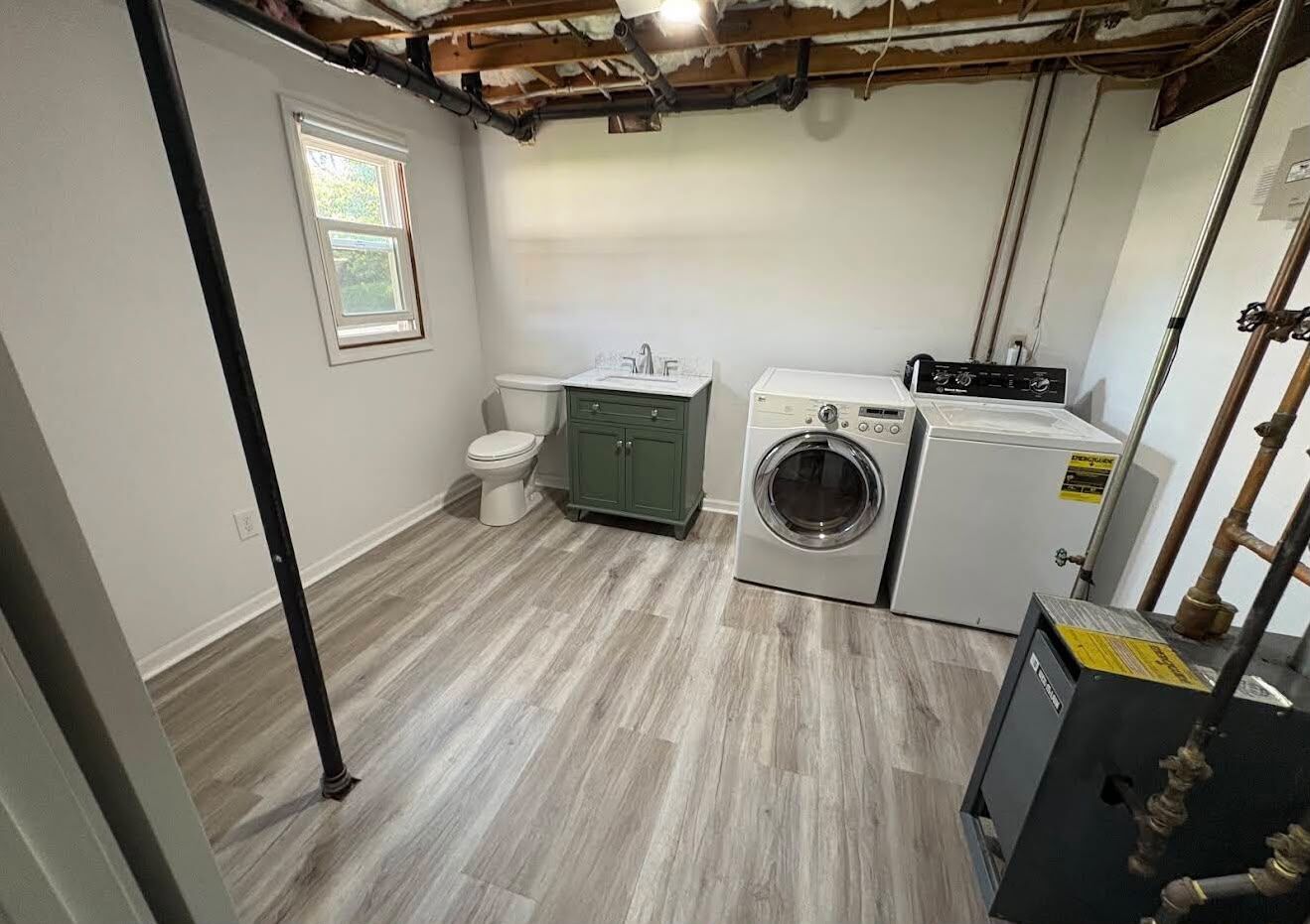 Finished basement laundry room with a toilet, green vanity, washer and dryer