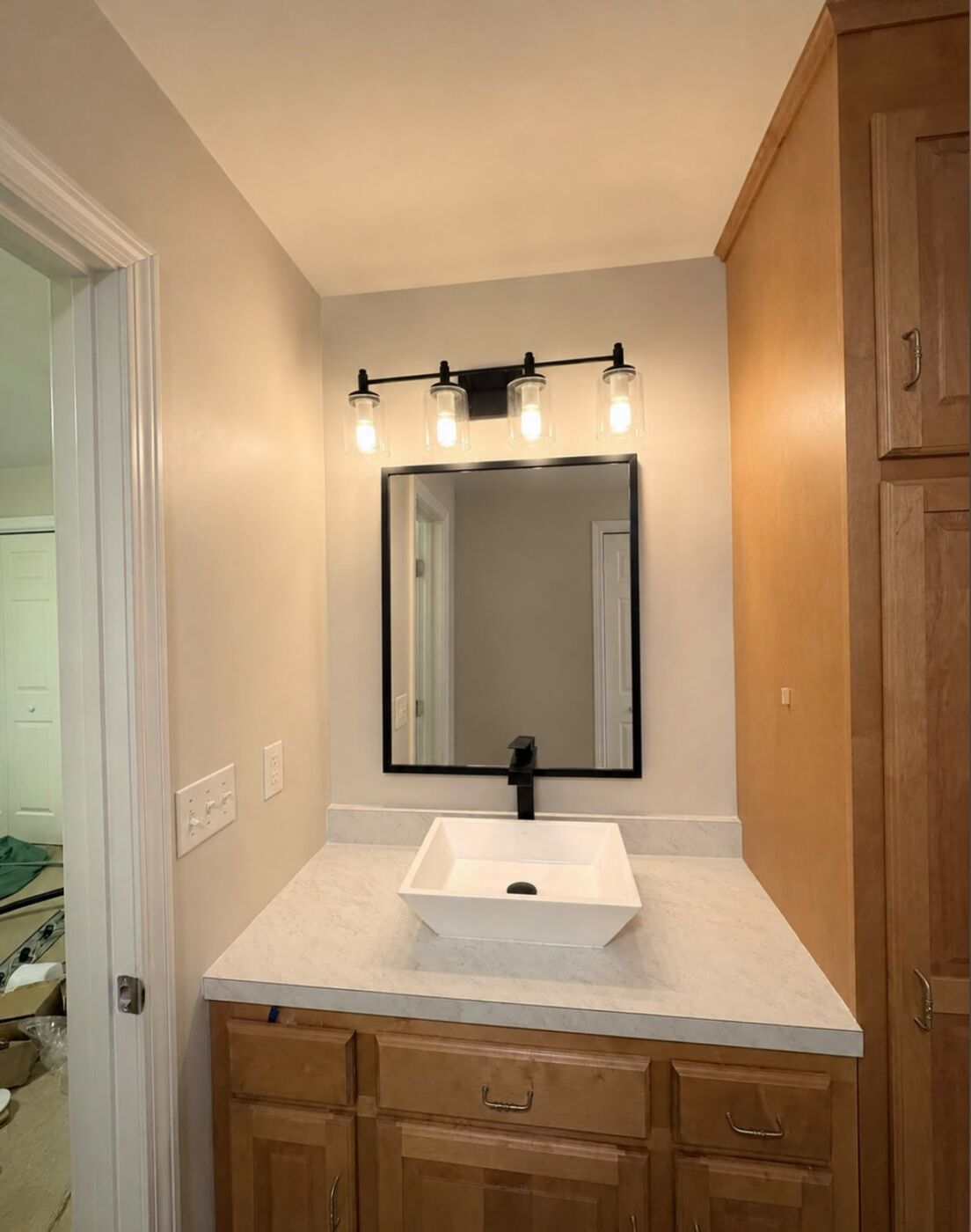 Small bathroom with a maple vanity, white vessel sink and black four-light vanity bar