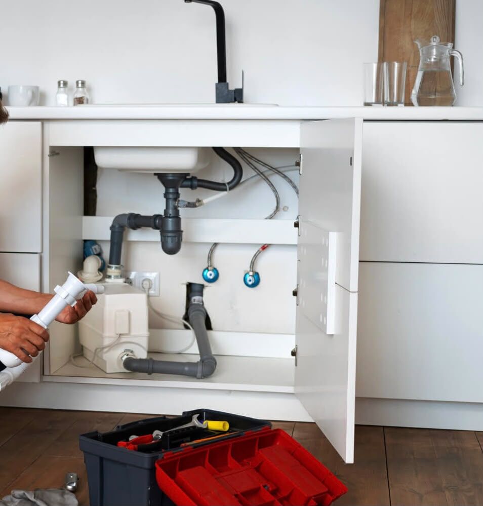 Under-sink cabinet with new drain piping, supply lines and a macerator pump