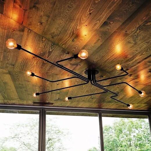 Black multi-arm industrial light fixture mounted on a wood plank porch ceiling